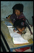 China, Tibet, Shigatse, Primary school children sitting at desks copying Tibetan handwriting.