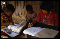 Thailand, North, Chiang Rai, Akha children doing homework.