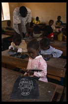 Mali, Pays Dogon, Tirelli, Children sitting at desks and teacher standing over in classroom at the school during french lessons.