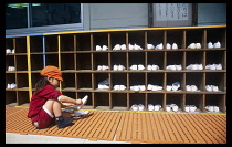 Japan, Honshu, Tokyo, Ryogoku. Nursery school with four year old girl putting on uwabaki shoes for wearing inside.
