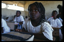 Angola, General, Young girl with braided hair writing at desk in school classroom.