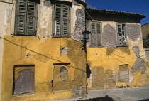 Greece, Attica, Athens, Plaka, Old buildings with crumbling yellow painted facade and shuttered windows.