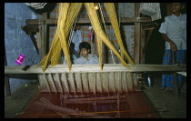 India, Uttar Pradesh, Varanasi, Child silk weavers working at loom in workshop.