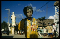 Belize, Ambergris Caye, San Pedro, Carnival. Boy covered in paint holding a plastic bottle  with others in the background.