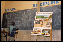 Mali, Pays Dogon, Tirelli, A boy standing at chalkboard in classroom leading chanting of a text in French lesson.