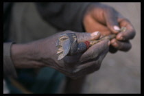 Mali, Pays Dogon, Amani, A pair of hands holding a finely carved hard wood pipe with bearded head design.