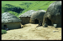 South Africa, Kwazulu Natal, General, Zulu kraal with children sitting outside thatched huts.