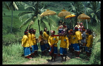 Indonesia, Bali, Ubud, Cremation procession with grandchildren of prince fetching holy water carried on litter with decorated golden sun shades accompanied by gamelan musicians.