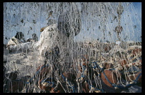 Mauritania, Fishing, Fisherman mending nets partly obscured behind tangled screen of lines.