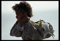 Mauritania, Fishing, Child carrying catch of fish in woven bag on her back.