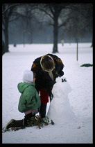 Children, Playing, Outside, Decorating snowman with holly in heavy snow in Hyde Park  London.