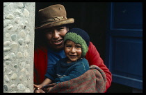 Peru, Cusco, Pisac, Inca mother and child standing in doorway smiling.