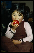 India, Kashmir, Children, Portrait of young girl eating famous Kashmir apple.