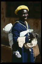 Mozambique, Children, Smiling young woman carrying baby in sling tied on her back.