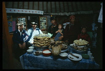 Mongolia, Gobi Desert, Family attired in their best clothes and singing for boy s haircutting ceremony  meal of fat-tailed sheep and flat bread laid out on table in home.    Traditionally marks the po...