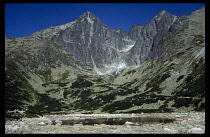 Slovakia, Carpathian Mts., Tatras Mountains, The High Tatras.  Small stretch of water at foot of scree slopes with jagged peaks above.