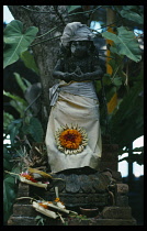 Indonesia, Bali, Religion, Statue of local deity set in small shrine with offerings in restaurant outside Besakih Temple.