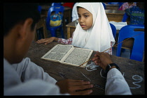 Thailand, Chiang Mai, Young girl studying the Koran in mosque.