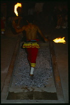 Sri Lanka, Kandy, Man taking part in fire walking ceremony crossing hot coals barefoot carrying lighted torches.