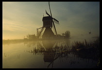 Holland, North, Groot Ammers Canal with a windmill in misty landscape.