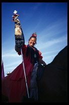 Spain, Andalucia, Huelva Province, Gypsey woman on horseback carrying the colours of the Brotherhood of Cadiz during the Romaria to the village of El Rocio.