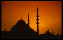 Turkey, , Istanbul, Orange sunset silhouetting the Yeni and Suleymaniye mosques.