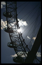 England, London, The London Eye capsules silhouetted against the sun.