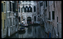 Italy, Veneto, Venice, Gondolier taking tourists through a side canal on his gondola past a small hotel.