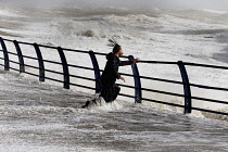 England, East Sussex, Hastings, Man braving the wild waves battering the promenade during storm.