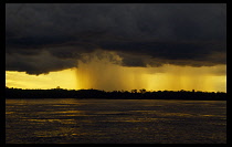 Brazil, Amazon, Rainstorm over the Amazon  low lying grey cloud and yellow light.