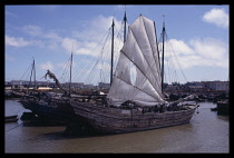 CHINA, Hainan Island, Haikou Harbour, Junk with torn white sail.