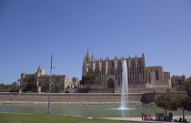 Spain, Balearic Islands, Majorca, Palma de Mallorca, Royal Palace of La Almudaina and La Seu Gothic Roman Catholic Cathedral of Santa Maria with fountain in the foreground.