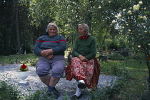 Estonia, Kihnu Island, Two peasant women seated on  bench in a cemetary.