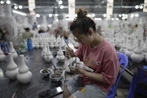 Vietnam, close to Hanoi, Ceramist painting a vase in a ceramic factory in Bat Trang ceramic village.