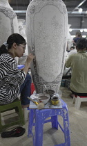 Vietnam, close to Hanoi, Ceramist painting a vase in a ceramic factory in Bat Trang ceramic village.