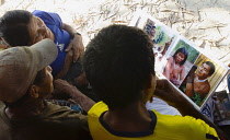 Colombia, Piraparana, Tukano indians looking at a photo book with pictures of their ancestors.