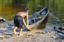 Colombia, Piaraparana, Tukano indian pushes canoe out.