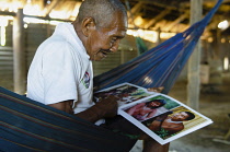 Colombia, Piraparana, Sta. Isabel, The shaman Ignacio looking at a photo book with pictures of himself and other Tukano indians.