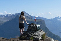 Norway-, Western Norway, Trekker admiring the view fron the summit of Saksa mountain with Breidfonnhornet in the background. Sæbø.