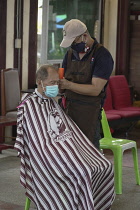 Thailand, Bangkok, Man receiving a hair cut at a barbers.