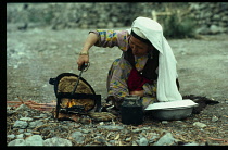 Afghanistan, General, Kirghiz nomad woman baking bread on outside fire.