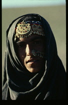 Afghanistan, General, Head and shoulders portrait of Afghan nomad woman wearing elaborate nose ring and head jewellery indicating bride wealth.