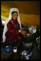 Afghanistan, General, Kirghiz nomad woman cooking on small stove inside yurt.