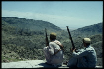 Afghanistan, Safed Koh, Khyber Pass, Armed Afridis on plateau of rock looking out over barren mountain landscape.