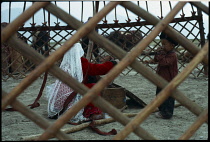 Afghanistan, General, Kirghiz woman and children inside frame of yurt seen through criss-cross lines of wall.