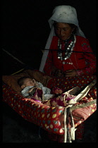 Afghanistan, General, Kirghiz woman inside yurt with young child in cradle.