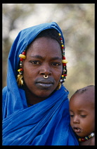 MALI, Niono, Fulani mother wearing gold earrings  beads and nose ring.