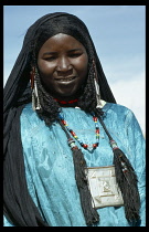 ALGERIA, General, Portrait of a woman wearing a black head scarf and long earrings with beaded and tassled necklaces.