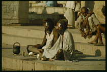 India, Uttar Pradesh, Varanasi, Holy men meditating beside the River Ganges.