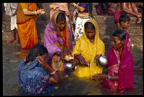 India, Uttar Pradesh, Varanasi, Women in colourful saris ritual bathing at dawn on the ghats of the River Ganges.